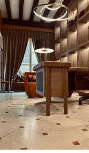 Bureau de luxe moderne/classique : sol marbre, étagères murales éclairées, plafond à poutres. Grande lampe de bureau et fauteuil confortable.