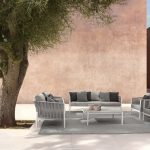 Thumbnail of http://Un%20coin%20salon%20extérieur%20contemporain%20comprenant%20un%20canapé,%20deux%20chaises%20et%20une%20table%20basse%20avec%20des%20coussins%20et%20oreillers%20de%20couleur%20neutre.%20Les%20meubles%20sont%20posés%20sur%20un%20tapis%20gris%20à%20côté%20d'un%20grand%20arbre%20feuillu.%20L'arrière-plan%20comprend%20des%20murs%20minimalistes%20brun%20rosé.