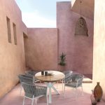 Thumbnail of http://Un%20patio%20extérieur%20minimaliste%20avec%20une%20table%20ronde%20en%20bois%20avec%20une%20base%20blanche,%20entourée%20de%20quatre%20chaises%20tressées%20grises.%20Le%20patio%20a%20des%20murs%20rose%20pâle,%20un%20luminaire%20suspendu%20en%20osier%20et%20une%20petite%20plante%20en%20pot%20en%20arrière-plan.%20Divers%20vases%20en%20céramique%20ornent%20le%20coin.