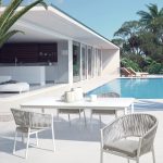 Thumbnail of http://Espace%20extérieur%20moderne%20comprenant%20une%20élégante%20maison%20blanche%20avec%20de%20grandes%20fenêtres,%20une%20piscine%20et%20des%20meubles%20de%20jardin.%20Le%20mobilier%20de%20jardin%20comprend%20une%20table%20et%20des%20chaises%20blanches%20avec%20des%20détails%20en%20corde%20gris%20clair.%20Il%20y%20a%20également%20des%20bougies%20et%20des%20objets%20décoratifs%20sur%20la%20table,%20sur%20fond%20de%20verdure%20luxuriante.