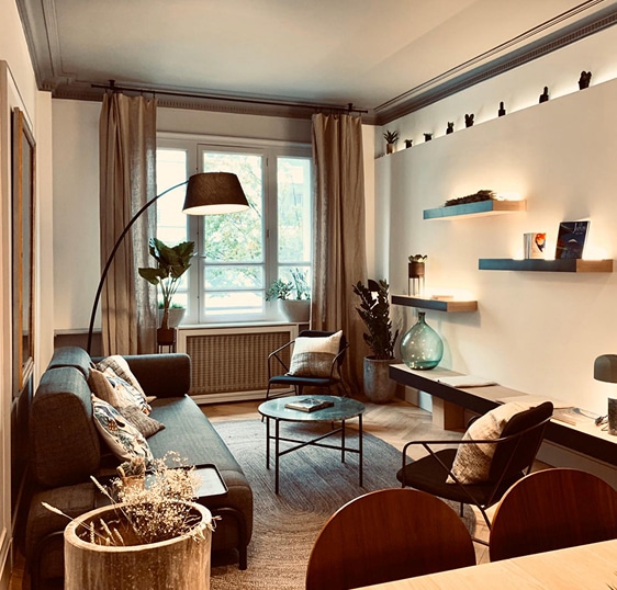 Décoration Salon moderne : Ambiance chaleureuse et éclairage design. Salon moderne et lumineux. Canapé gris, fauteuils noirs, lampadaire arqué, étagères flottantes LED et moulures au plafond. Ambiance chaleureuse.