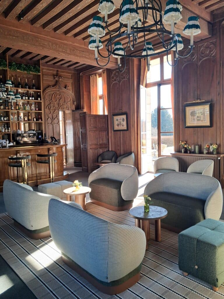 Bar de Luxe : Design Moderne et Boiseries Anciennes Salon élégant avec boiseries, bar en bois et mobilier moderne baigné de lumière naturelle.